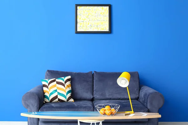 客厅内蓝色墙壁附近的沙发和冲浪板 配有时尚灯和橙子 — 图库照片