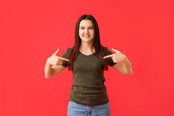 Jonge Vrouw Wijst Naar Shirt Rode Achtergrond — Stockfoto