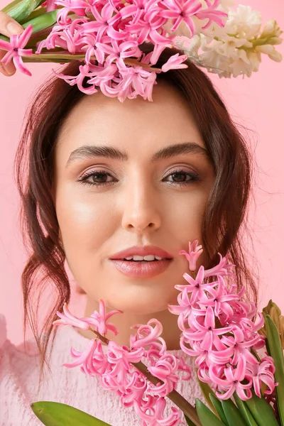 ピンクの背景にヒヤシンスの花を持つかなり若い女性 — ストック写真