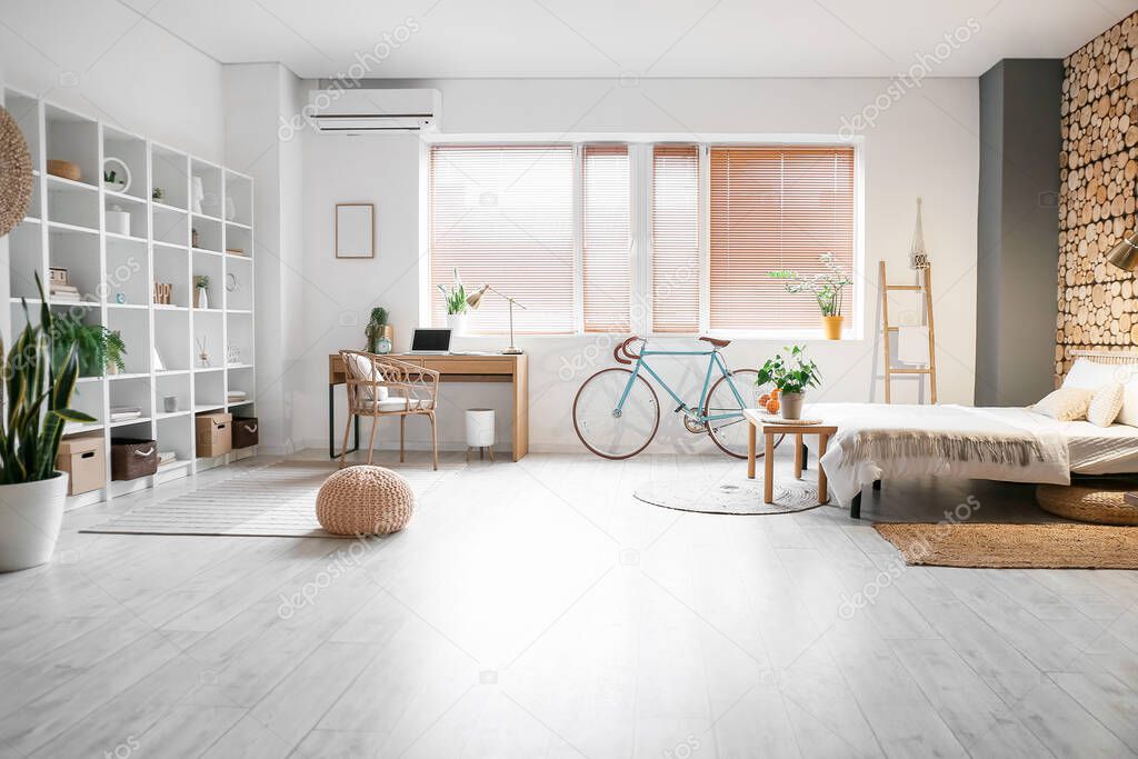 Interior of modern  studio apartment with bicycle, bed and workplace