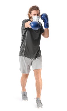 Beyaz arka planda tıbbi maske takan ve boks eldiveni takan genç bir adam. Güçlü bağışıklık kavramı