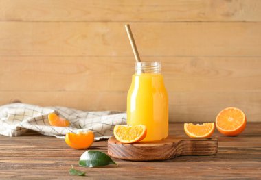 Ahşap arka planda bir şişe taze mandalina suyu.