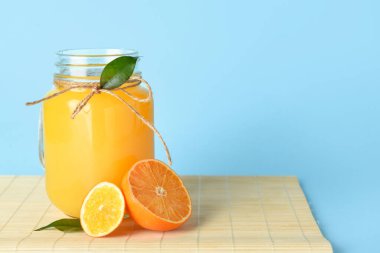 Mavi arka planda bir kavanoz taze mandalina suyu, yakın plan.