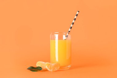 Turuncu arka planda bir bardak taze mandalina suyu