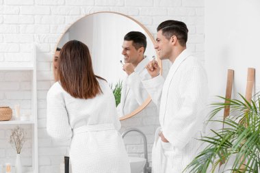 Genç bir çift banyoda aktif kömür diş macunu ile dişlerini fırçalıyor.