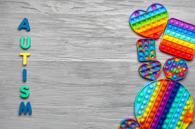 Kelime AUTISM Gri ahşap arka planda kıpırdayan oyuncaklar
