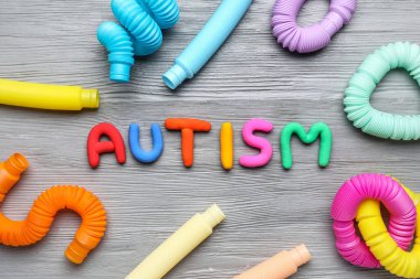 Gri ahşap arka planda pop tüpleriyle AUTISM