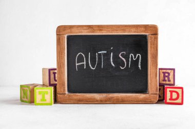 Beyaz arkaplanda kelime AUTISM ve küp yazılı tebeşir tahtası