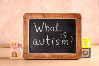 Metinli tebeşir tahtası. AUTISM nedir? ve renk arkaplanındaki küpleri