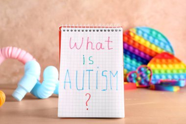Metinli defter. AUTISM nedir? ve renkli arkaplanda oyuncaklar