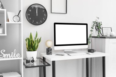 Bilgisayarlı işyeri, vazoda okaliptüs dalı ve ışık duvarı yakınında lamba