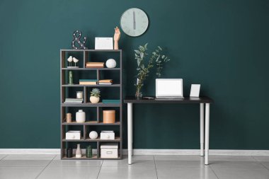 Çalışma yeri, dizüstü bilgisayarı ve raf ünitesi olan şık bir ofis.