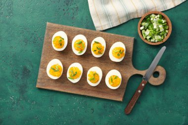 Doldurulmuş yumurta, yeşil soğan ve yeşil arka planda bıçak. Paskalya kutlaması