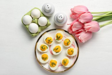 Beyaz ahşap arka planda içi doldurulmuş yumurta tabağı. Paskalya kutlaması