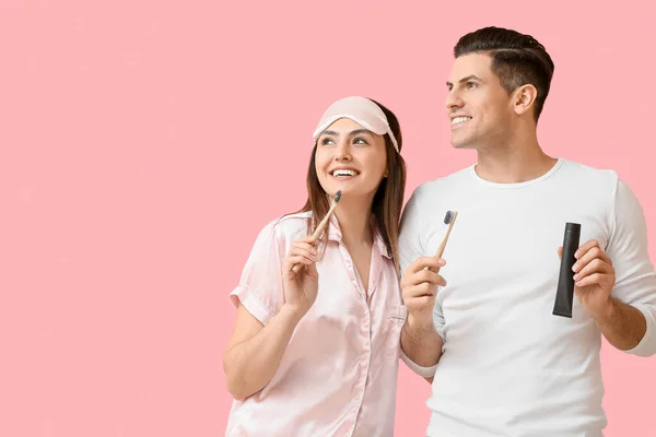 年轻夫妇用活性炭牙膏和粉红背景刷牙 — 图库照片