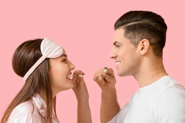 粉红底色活性炭牙膏刷牙的年轻夫妇 — 图库照片