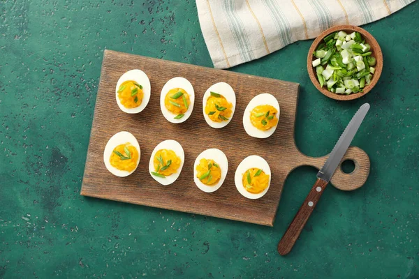 Doldurulmuş yumurta, yeşil soğan ve yeşil arka planda bıçak. Paskalya kutlaması