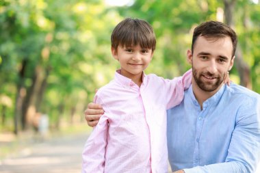 Baba parkta oğluna sarılıyor.