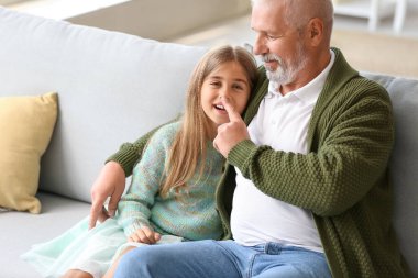 Büyük adam evde torununun burnuna dokunuyor.