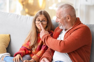 Büyük adam evde torununun burnuna dokunuyor.