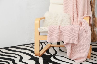 Hafif duvarın yanında pembe ekose koltuklu.