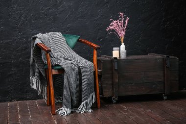 Koltuklu, ekoseli ve çekmeceli karanlık odanın içi.