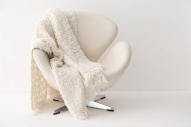 Hafif duvarın yanında beyaz ekose koltuklu.