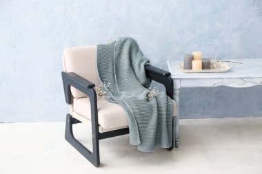 Ekoseli koltuk, çiçekler, masa ve ışık duvarının yanındaki mumlar.