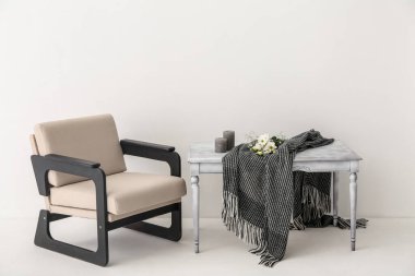 Ekoseli masa, çiçekler, mumlar ve ışık duvarının yanındaki koltuk.