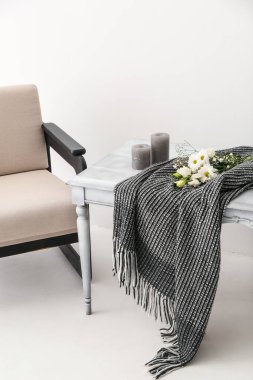 Ekoseli masa, çiçekler, mumlar ve ışık duvarının yanındaki koltuk.