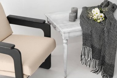 Ekoseli masa, çiçekler, mumlar ve ışık duvarının yanındaki koltuk.