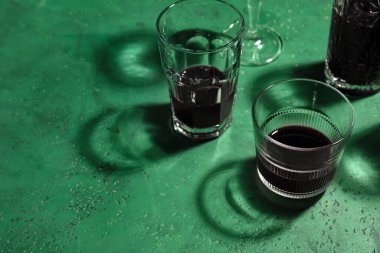 Yeşil arka planda alkollü farklı bardaklar.