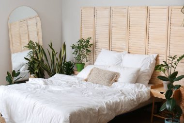 Ev bitkileri ve katlanan ekran ile aydınlık yatak odasının içi