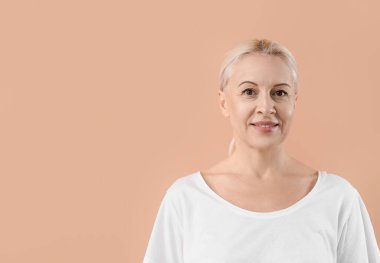 Bej arka planda sağlıklı ciltli olgun sarışın kadın.