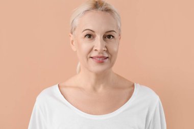 Bej arka planda sağlıklı ciltli olgun sarışın kadın.