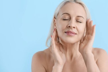 Mavi arka planda sağlıklı ciltli olgun sarışın kadın, yakın plan.