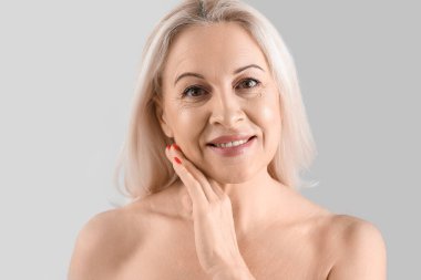 Açık arkaplanda sağlıklı cilde sahip olgun sarışın kadın, yakın plan.