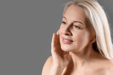 Koyu arkaplanda sağlıklı ciltli olgun sarışın kadın, yakın plan.