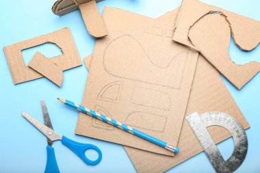 Mavi arka planda karton uçak oyuncağı yapmak için malzemeler