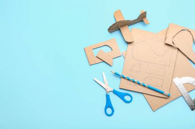 Mavi arka planda karton uçak oyuncağı yapmak için malzemeler