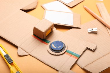 Turuncu arkaplanda karton fotoğraf makinesi, yakın plan.