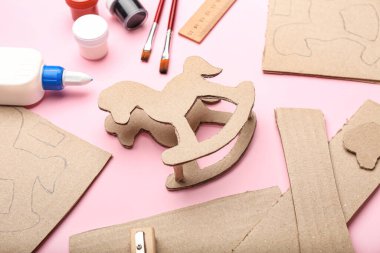 Karton sallanan atı pembe arka planda yapmak için malzemeler