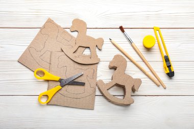 Beyaz ahşap arka planda malzemesi olan karton sallanan at.