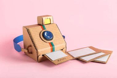 Pembe arkaplanda resimli karton fotoğraf makinesi.