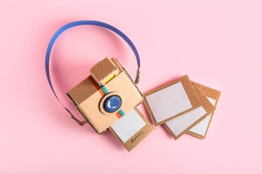 Pembe arkaplanda resimli karton fotoğraf makinesi.