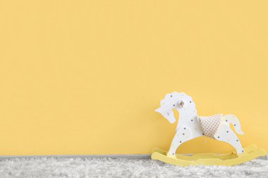 Sarı duvarın yanındaki yumuşak halıda sallanan at.