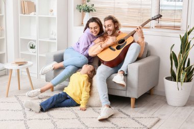 Mutlu genç aile evde gitar çalıyor.
