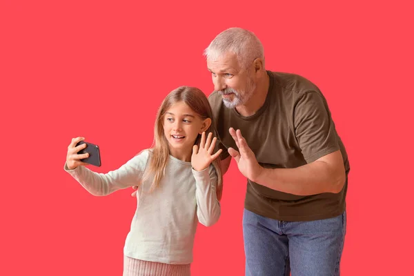 Kleines Mädchen Mit Ihrem Großvater Macht Selfie Auf Rotem Hintergrund — Stockfoto