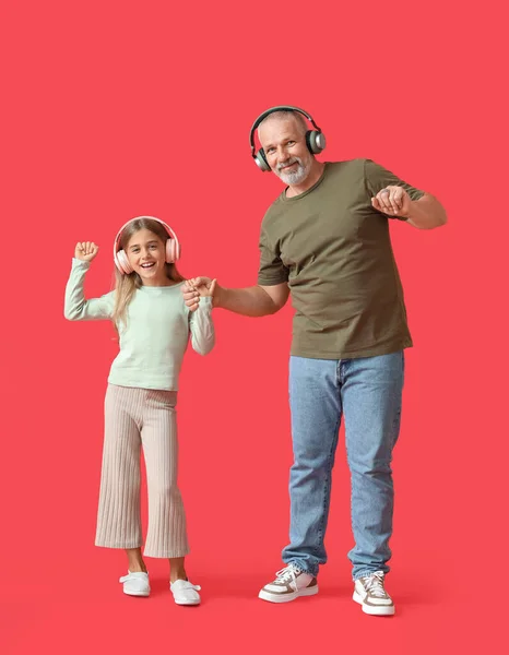 Κοριτσάκι Και Παππούς Της Ακουστικά Χορεύουν Κόκκινο Φόντο — Φωτογραφία Αρχείου