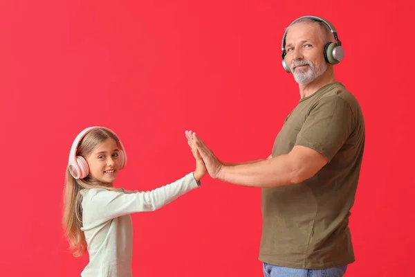 Μικρό Κορίτσι Και Παππούς Της Ακουστικά Κόκκινο Φόντο — Φωτογραφία Αρχείου